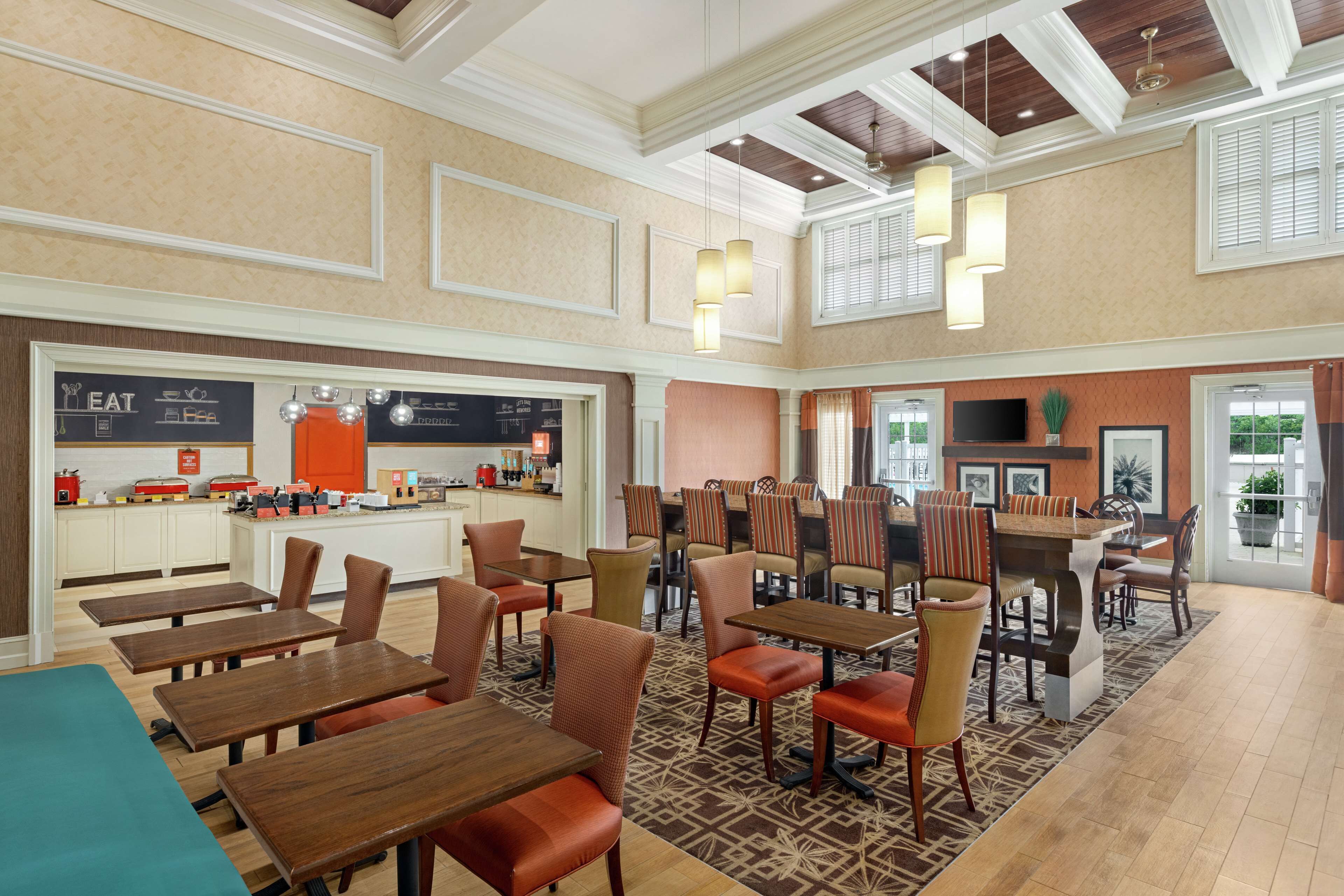 A spacious dining area with multiple tables and chairs, a counter with a menu, and a television screen.