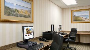 A conference room with a desktop computer, a printer, and two framed landscape paintings on the wall.