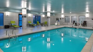 Ein Schwimmbecken mit klarem, blauem Wasser, umgeben von Liegestühlen und einem Umkleideraum.