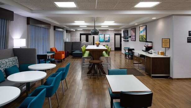 Eine moderne Hotelhalle mit einer zentralen Gastronomie, Sitzgelegenheiten und einer Küchenzeile.