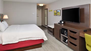 Una habitación de hotel con cama, televisión, escritorio y espejo.