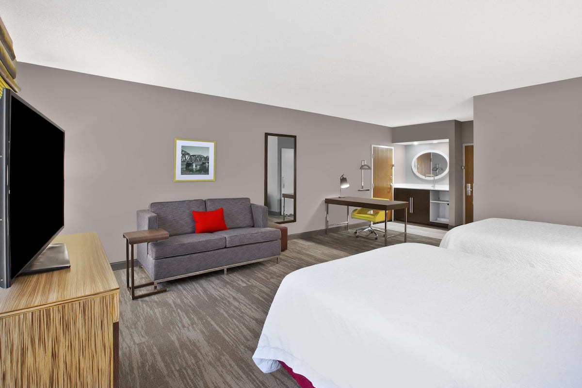 Une chambre d’hôtel avec un grand lit, un canapé, un bureau, une télévision et un miroir.