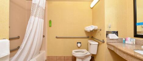 A bathroom with a shower, toilet, and sink, equipped with a handrail and a towel rack.