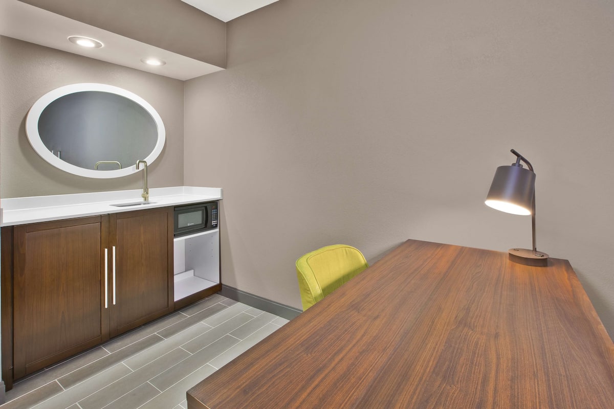 Une cuisine moderne dotée d’un plan de travail en bois, d’un évier, d’un four à micro-ondes et d’un miroir rond.
