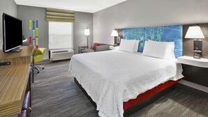 A hotel room with a large bed, a desk, a chair, a TV, and a window with blinds. - Hampton Inn & Suites Springboro/Dayton Area South (Springboro)