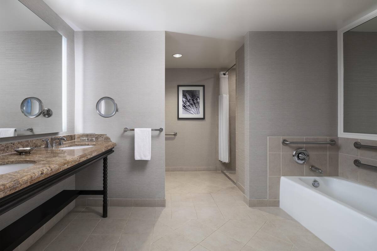 A modern bathroom with a double sink vanity, a bathtub, and a shower area.
