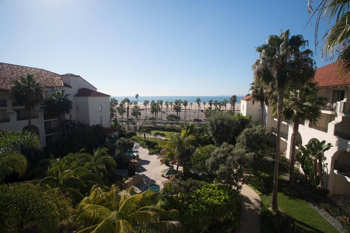 A resort with a pool, palm trees, and a view of the beach.