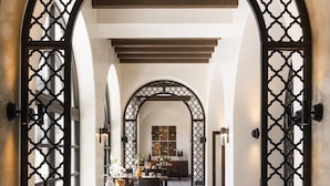 An arched corridor with a dining area featuring tables and chairs, a kitchen in the background, and decorative lattice screens. - Hyatt Regency Huntington Beach Resort and Spa (Huntington Beach)