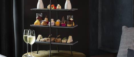 Een gelaagde dessertpresentatie op een rond tafel met een gevlochten onderzetter, vergezeld van twee glazen witte wijn.