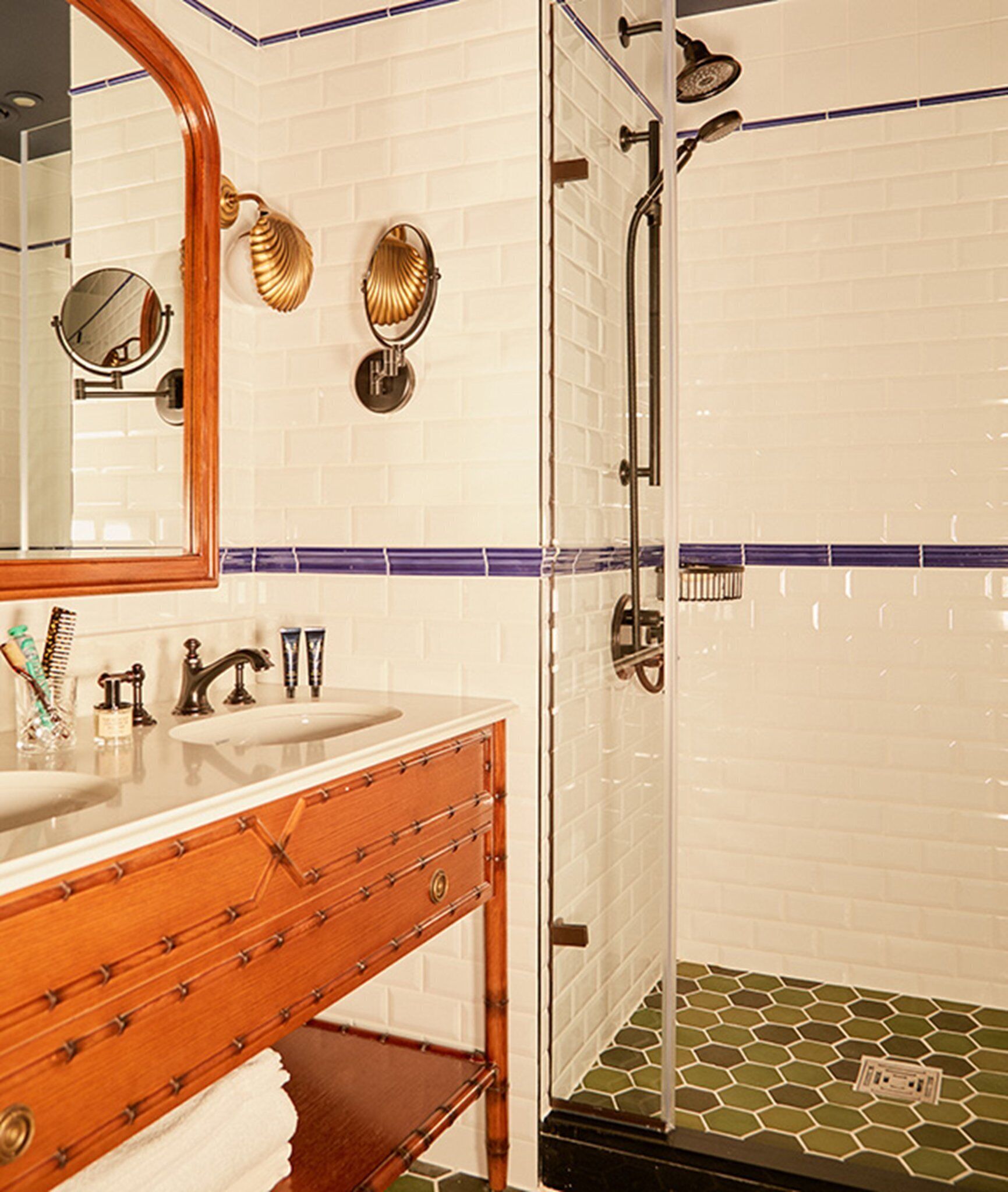 A bathroom with a wooden vanity, a large mirror, and a shower with a glass door.