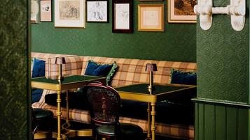 A room with a green wall, a wooden bench, a table, and chairs.