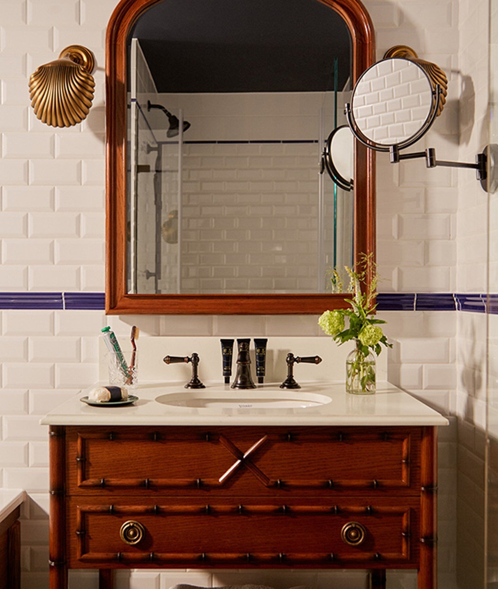 A bathroom with a wooden vanity, a large mirror, and two wall-mounted mirrors.