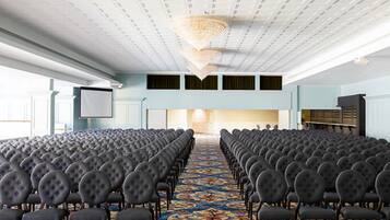 A conference room with rows of chairs, a patterned carpet, and a large chandelier.