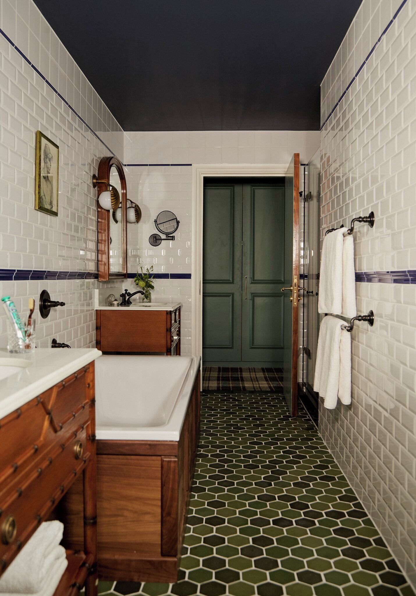 A bathroom with a white sink, wooden vanity, and a green door.