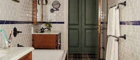 Un baño con lavamanos blanco, tocador de madera y una puerta verde.