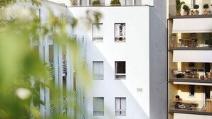 Un edificio moderno de varios pisos con balcones, ventanas amplias y un jardín en la azotea.