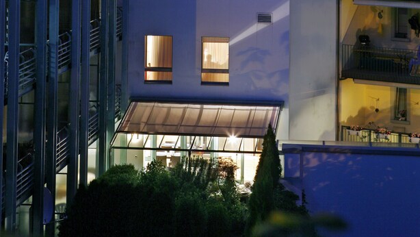 Un edificio moderno con numerosas ventanas y balcones, que presenta fachada de vidrio y techo plano.