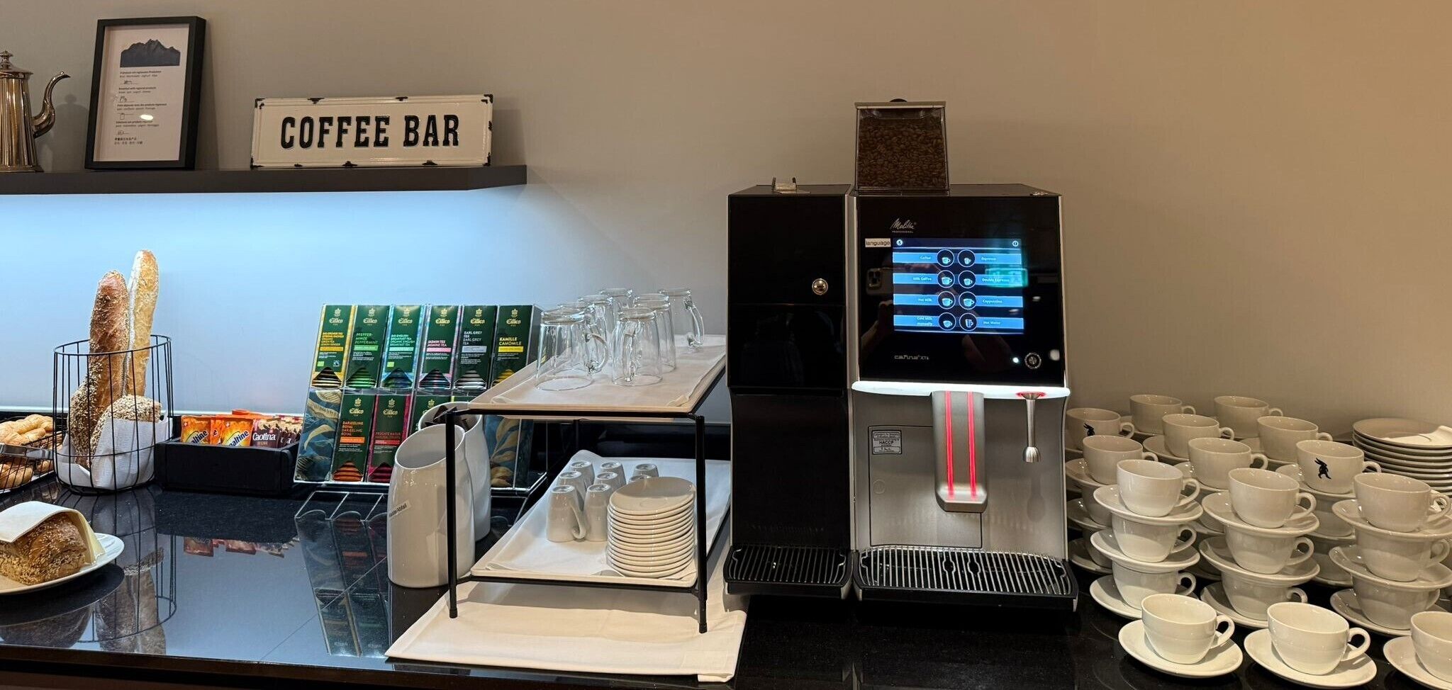 Ein Coffeeshop mit einer Kaffeemaschine, Tassen und Untertassen. Ein Schild zeigt 'COFFEE BAR'.