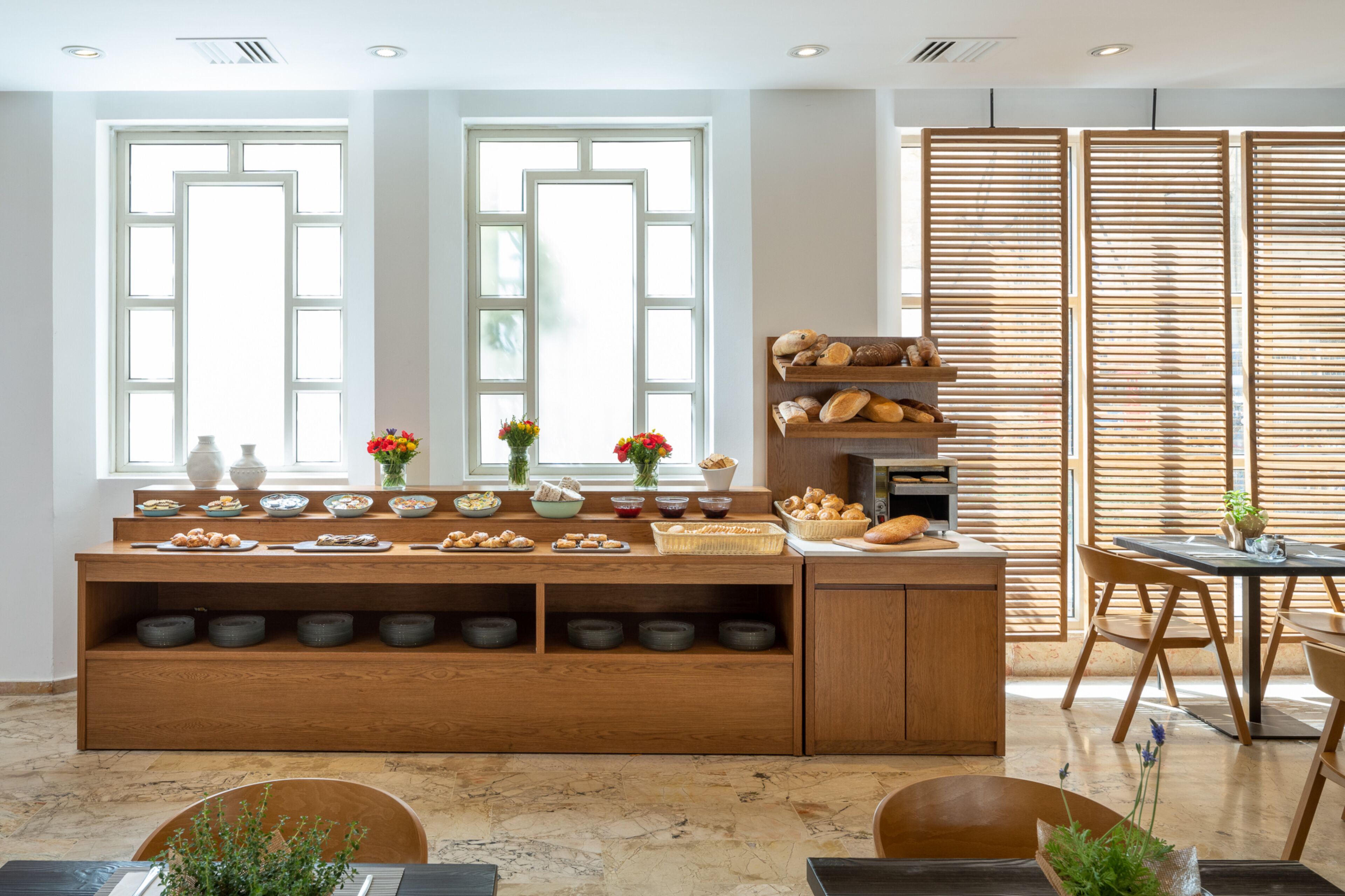 A modern kitchen with a wooden island, large windows, and a dining area with a table and chairs.