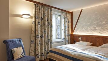 Ein Schlafzimmer mit Bett, Stuhl und Vorhängen.