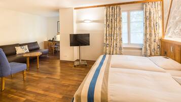 Een hotelkamer met een bed, een bank, een klein tafeltje, een televisie en een raam met gordijnen.