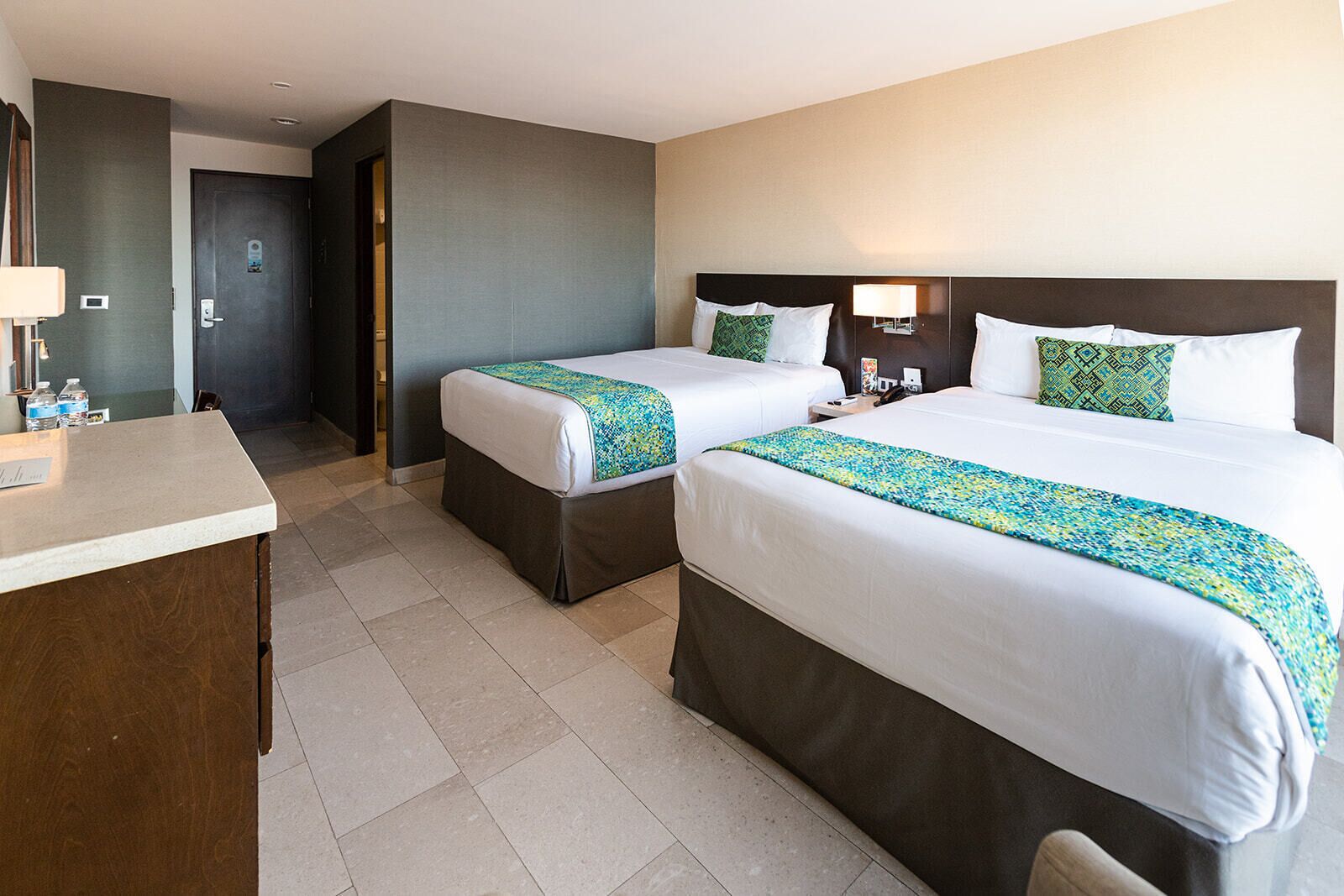 Une chambre d’hôtel avec deux lits, un bureau et une porte de salle de bain.