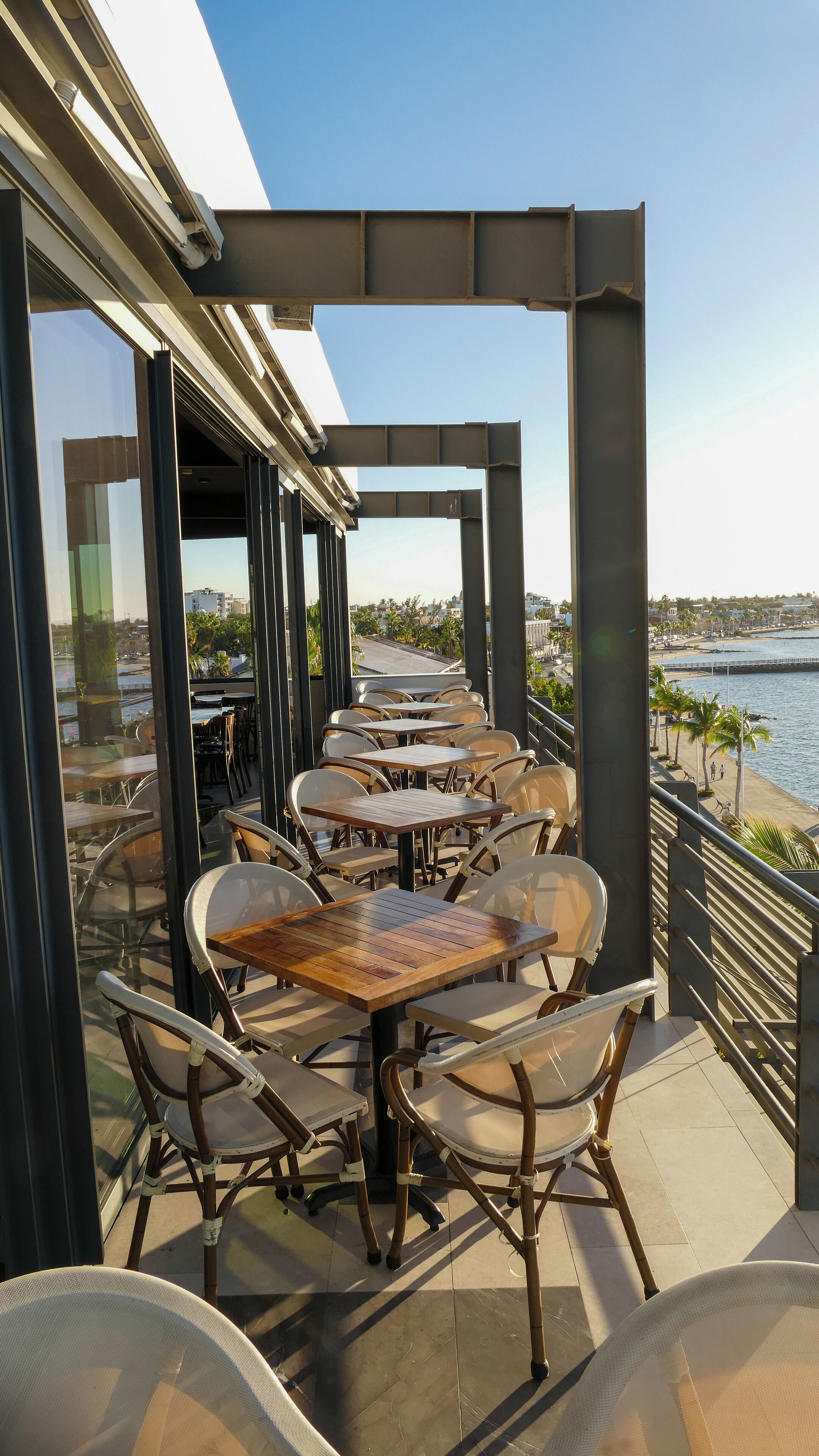 An outdoor dining area with tables and chairs, overlooking a waterfront.