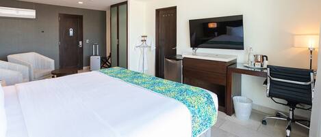 A hotel room with a bed, a desk, a chair, a TV, and a bathroom.