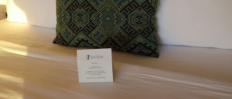 A hotel bed with a patterned pillow and a non-smoking room sign.