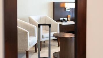 A hotel room with a bed, a chair, a table, and a suitcase.