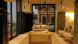 Una habitación de hotel moderna con un ventanal grande, un sofá, una silla y una cesta de mimbre.