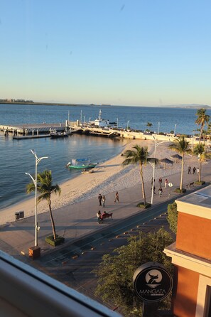 Vista costera con playa, muelle y un cartel que dice 'Mangata'.