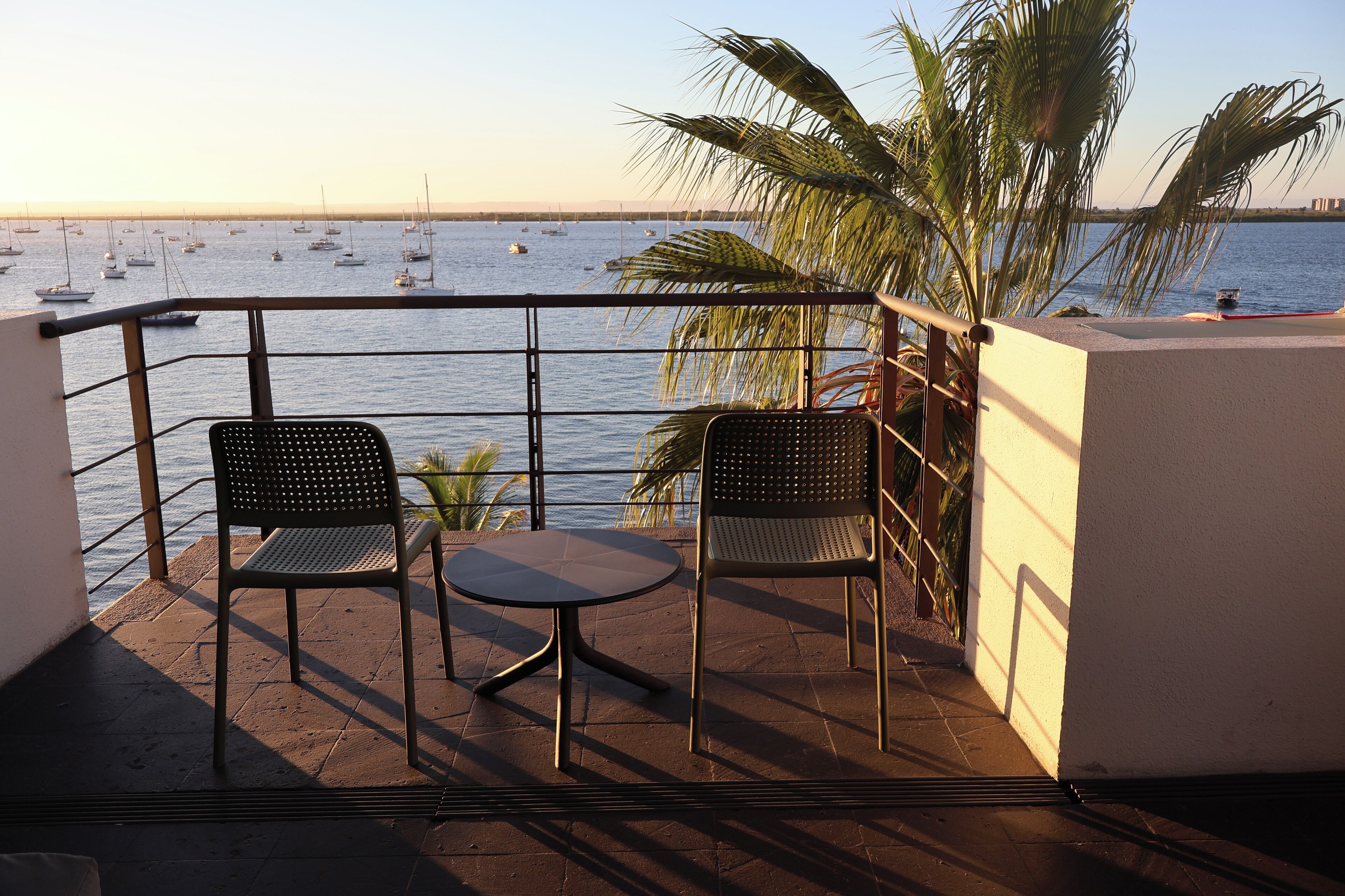 A balcony with two chairs and a small table, overlooking a marina with boats.