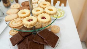 A glass display stand with assorted cookies and chocolate pieces.