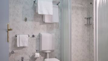 Een badkamer met douche, bidet, toilet en handdoekhouder.