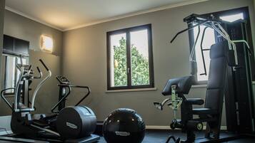 Una palestra con attrezzature per allenamento, tra cui tapis roulant, ellittica e macchina per pesi.