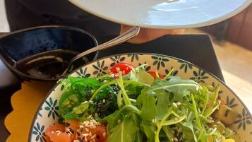 Un plato de comida con ensalada y otro plato de pasta.