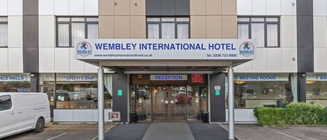 The entrance to Wembley International Hotel with a reception area, parking, and a sports bar.