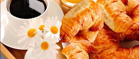 Ein Tablett mit Croissants, einer Tasse Kaffee und einem Glas Orangensaft.