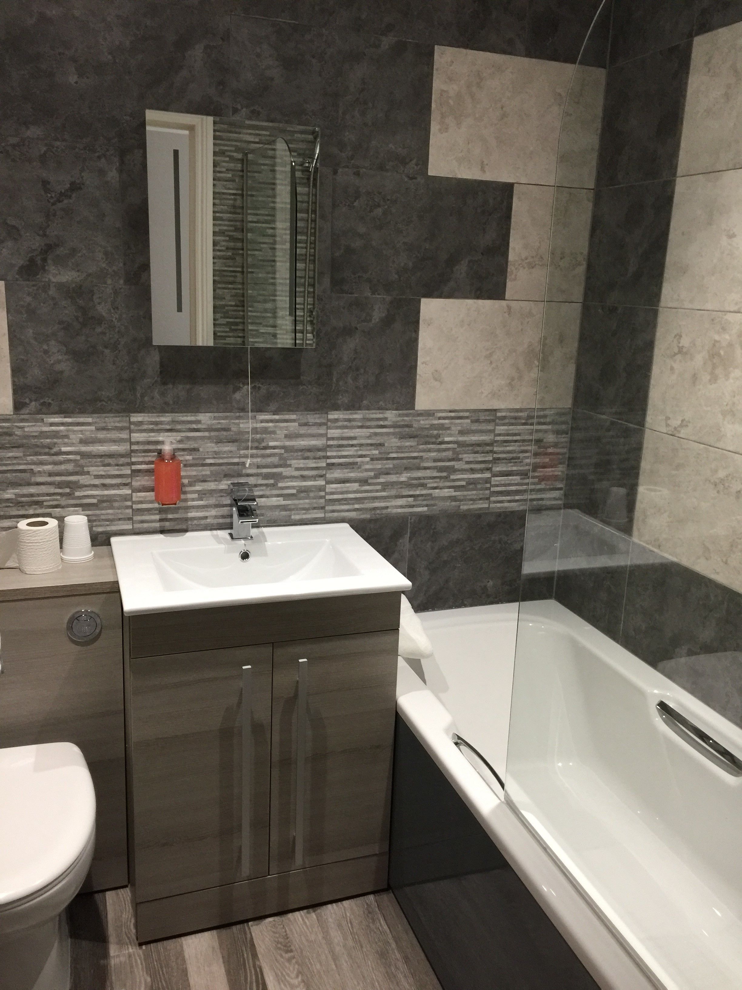 A modern bathroom with a white sink, dark wood cabinets, a glass shower enclosure, and a tiled backsplash.