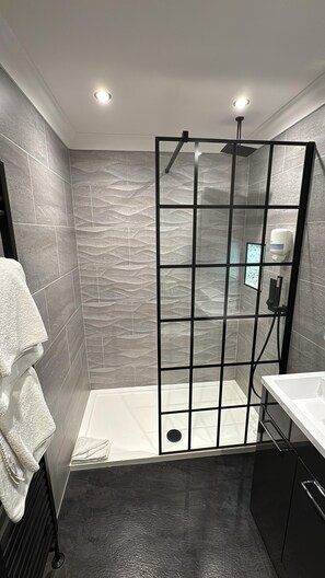 Un baño moderno con cabina de ducha, bañera blanca y tocador negro.