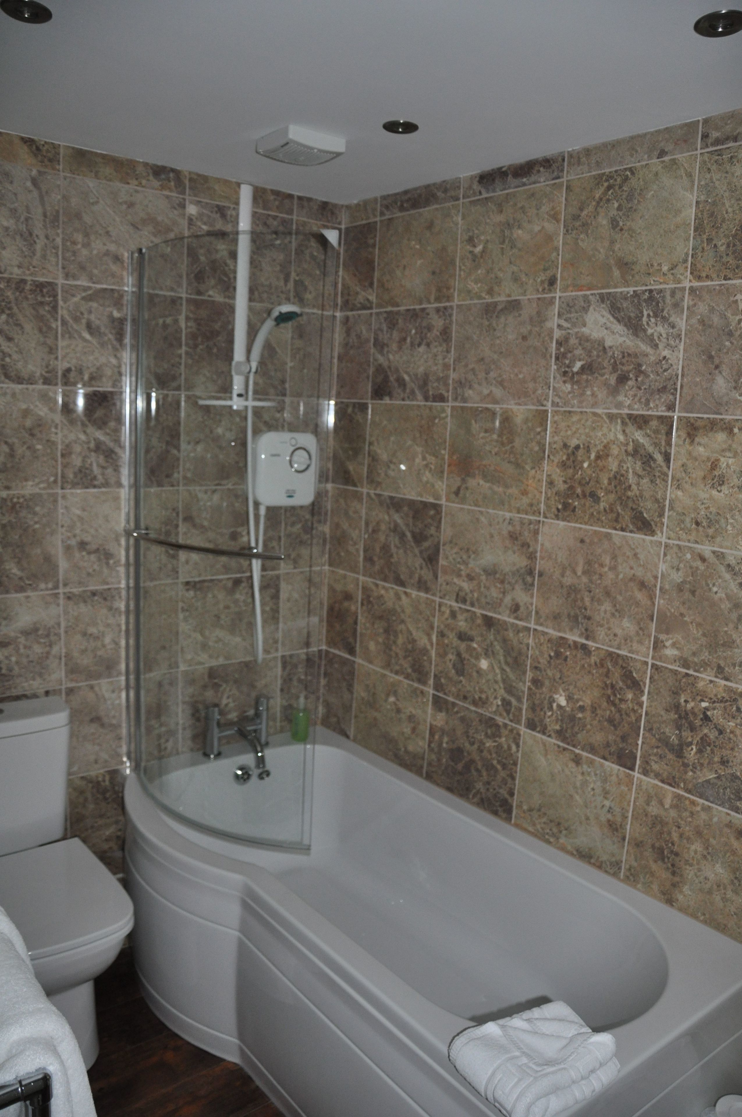 A bathroom with a glass-enclosed shower, a white toilet, and a bathtub with a towel.