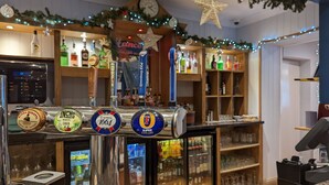 Eine Bar mit mehreren Zapfhähnen, einer Uhr und Regalen voller Flaschen.