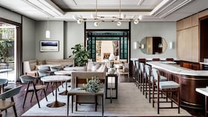 A modern hotel lobby with a bar, seating area, and a view of the outdoor garden. - The Ambrose (Santa Monica)