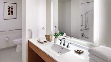 Un baño moderno con un lavabo blanco, un espejo grande, una ducha y un inodoro.