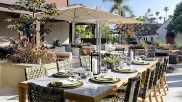 Un espacio de comedor al aire libre con una mesa larga dispuesta para seis personas, rodeado de sillas de mimbre.