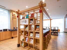 Una biblioteca con estanterías de madera, un letrero para un café biblioteca y vistas al exterior a través de grandes ventanales.