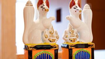 Two white ceramic cat figurines with gold accents on a colorful base.