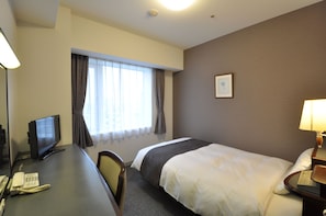 Une chambre d’hôtel équipée d’un lit, d’un bureau, d’une chaise et d’un téléviseur.