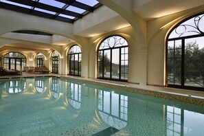 An indoor swimming pool with arched windows and a skylight. - Relais Villa Monte Solare Wellness & SPA (Panicale)